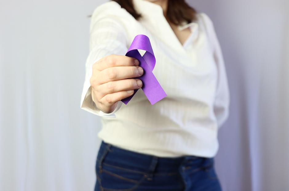 Woman wearing casual clothes holding in the hands a purple ribbon. Overdose awareness concept