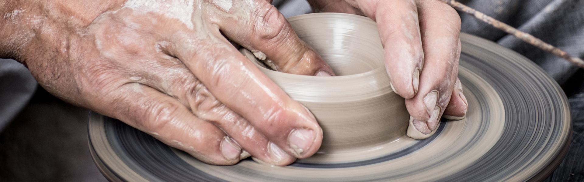 Using hand to form clay in to pottery on potter's wheel