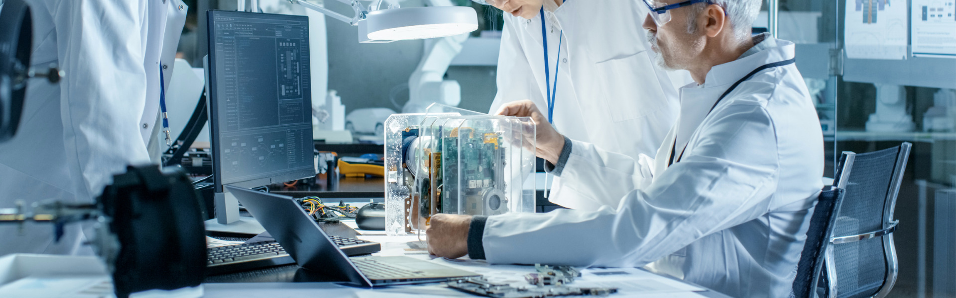 Team of Scientists Choose Between Printed Circuit Board to Work With. In The Background Technologically Advanced Scientific Research Center