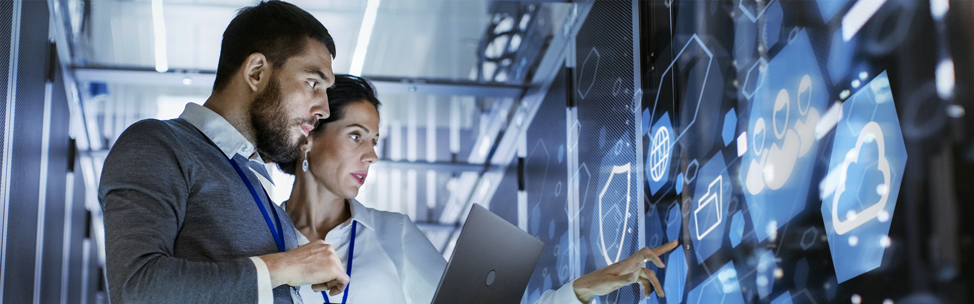 Male IT Specialist Holds Laptop and Discusses Work with Female Server Technician. They're Standing in Data Center, Rack Server Cabinet with Cloud Server Icon and Visualization. 