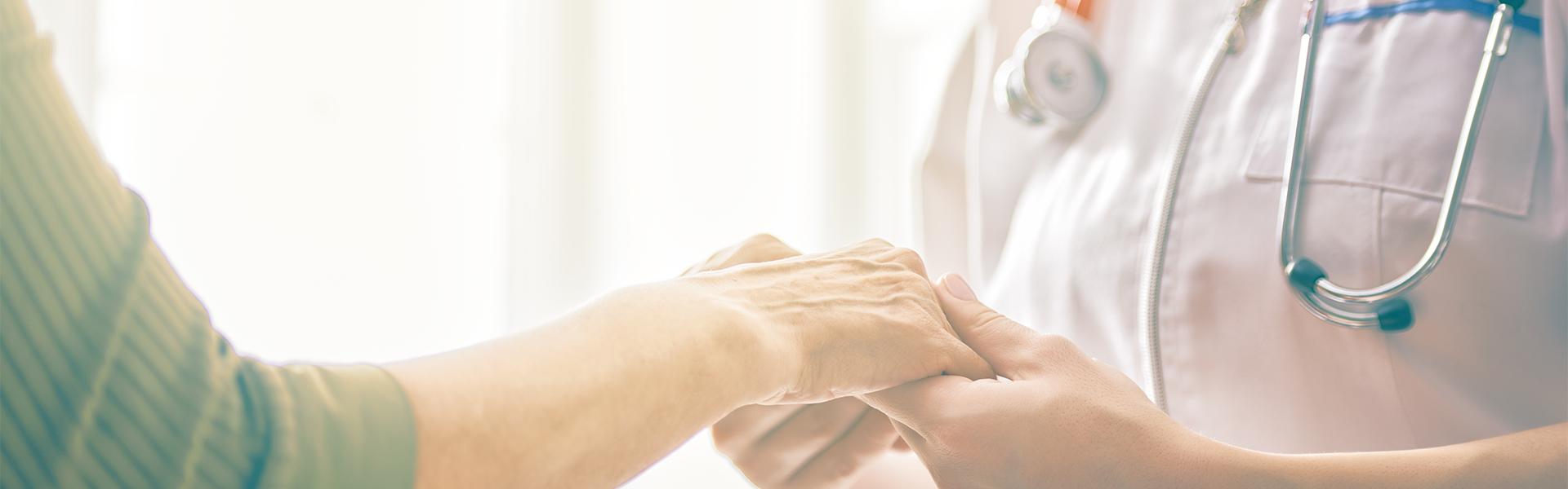 A nurse holding an elder's hand showing care