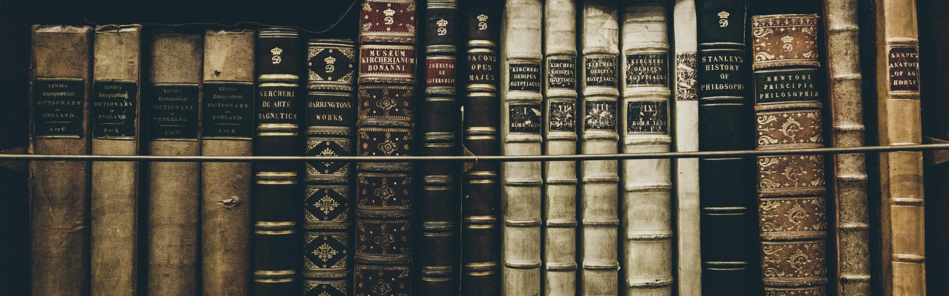 A row of historical books sitting on a shelf.