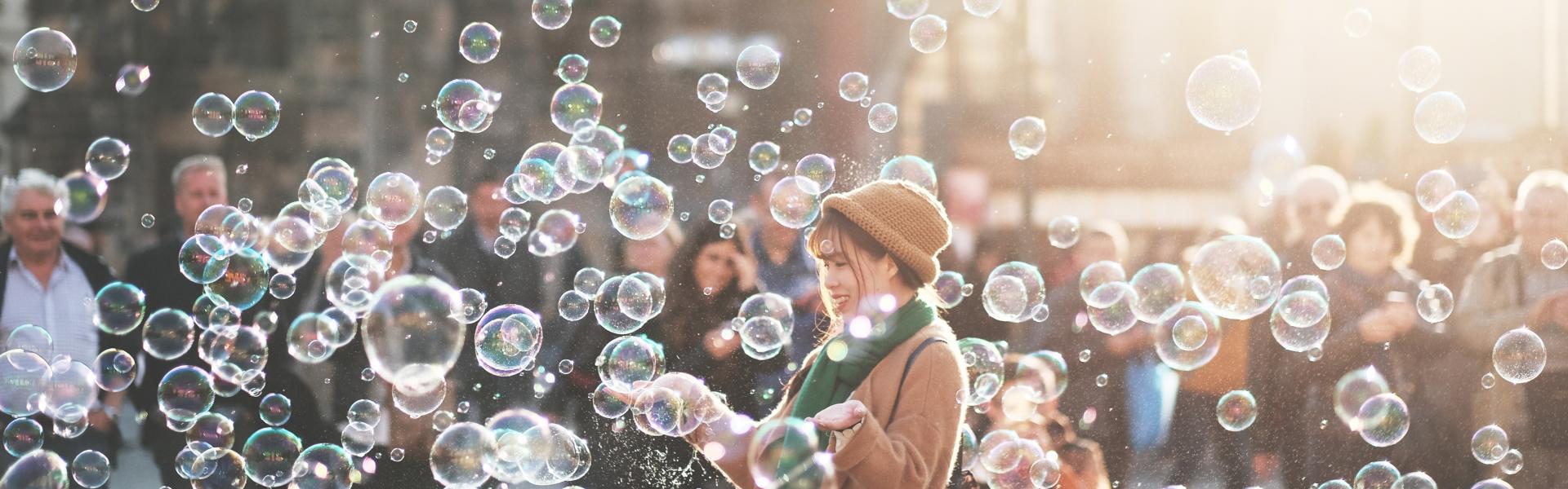 A woman standing in a crowd surrounded by bubbles.