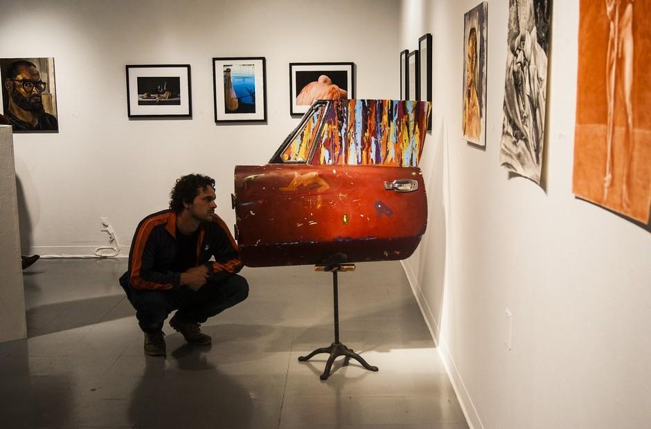 A man kneeling down to look at piece of artwork.