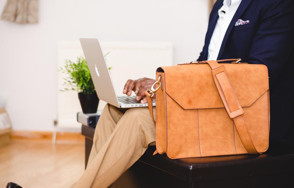 A business man with a suitcase working on a laptop