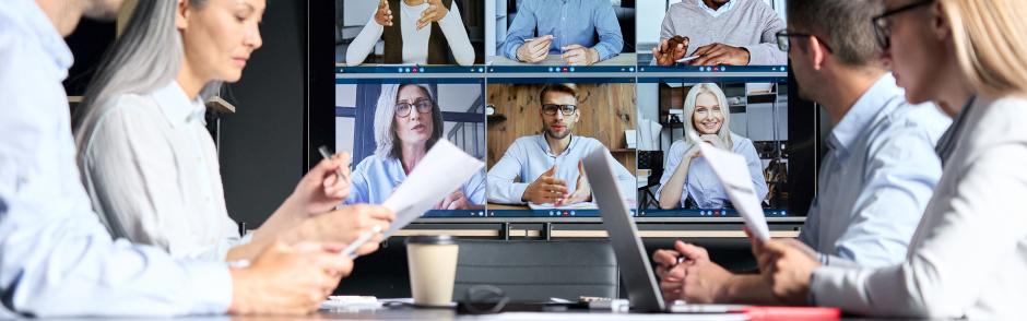 Global corporation online videoconference in meeting room with diverse people sitting in modern office and multicultural multiethnic colleagues on big screen monitor. Business technologies concept. 