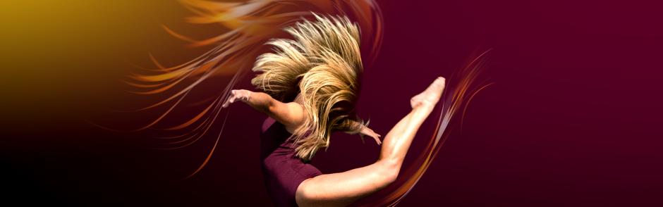 A dancer in a purple leotard with her hair flowing behind her.