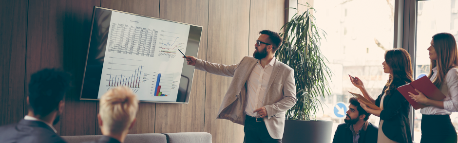 A men doing presentation about business information using data on the screen to explain to his teammates