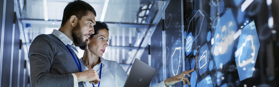 Male IT Specialist Holds Laptop and Discusses Work with Female Server Technician. They're Standing in Data Center, Rack Server Cabinet with Cloud Server Icon and Visualization. 