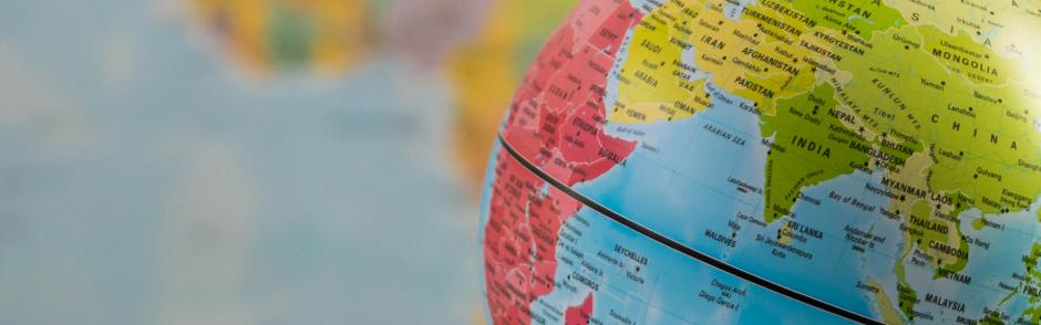 an earth globe focused on India with a blurred world map background