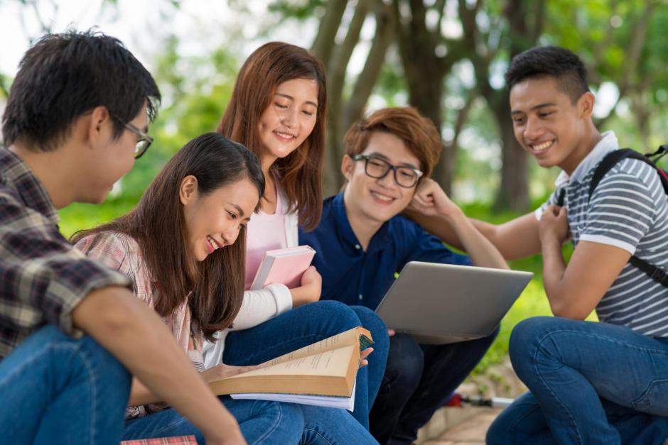 Cheerful classmates listening how girl reading students book aloud