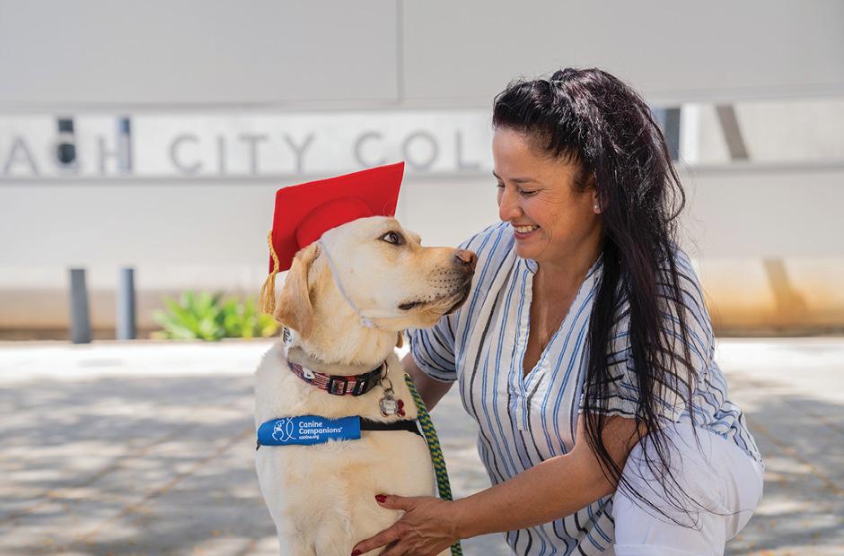 A women next to a dog with graduation cap smiling and looking at each other