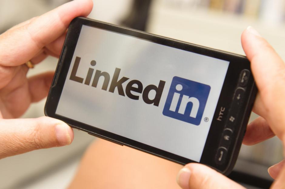 hands holding a contemporary smartphone that showing the linkedin.com logo on the display