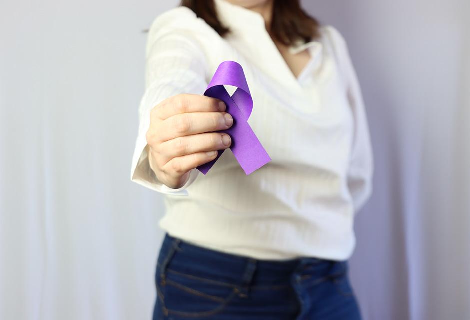 Woman wearing casual clothes holding in the hands a purple ribbon. Overdose awareness concept