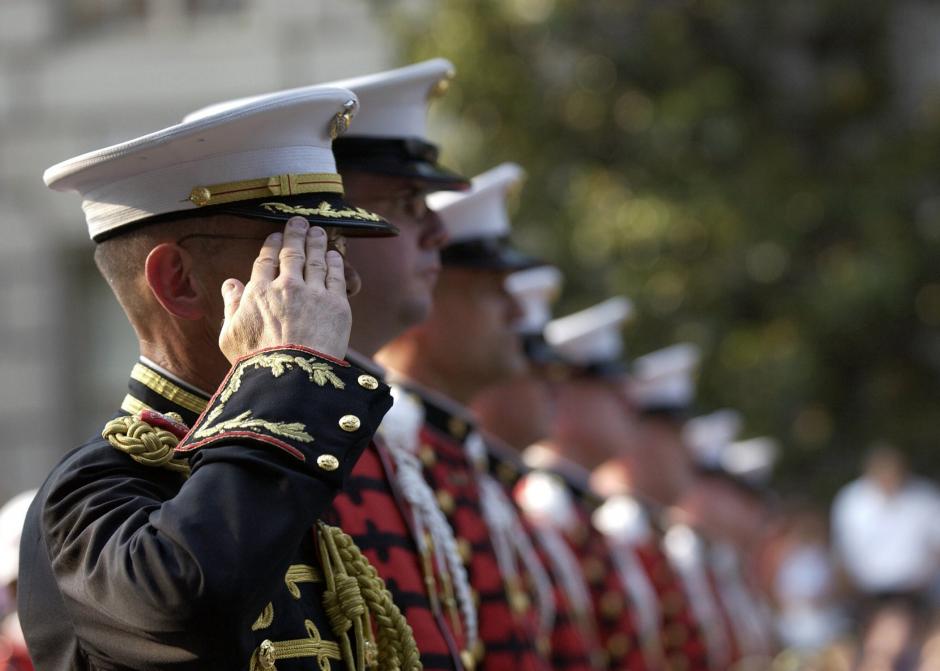 A group of Marines in uniform standing in line and saluting.