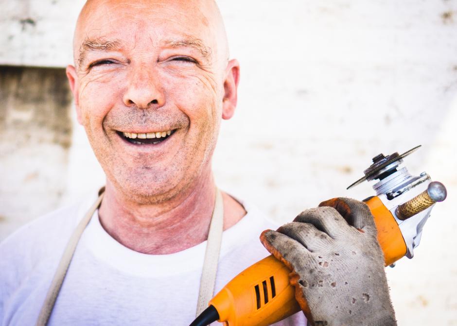 A man smiling and holding a tool