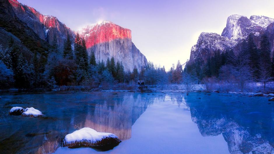 A mirrored lake surrounded by snow-covered mountains