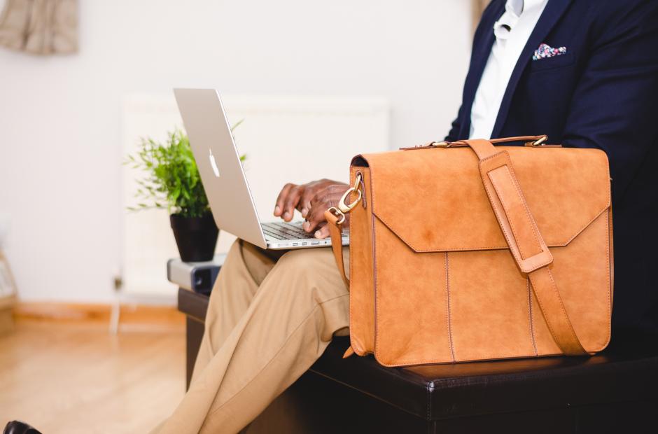 A business man with a suitcase working on a laptop