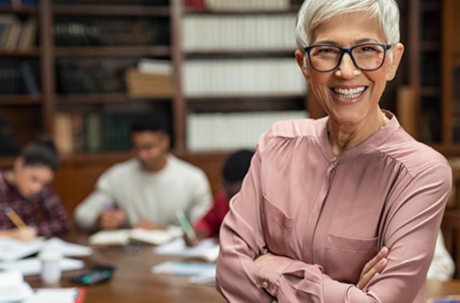 Smiling college professor helping students in library 