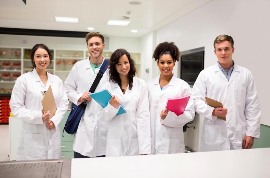 A group of scientists wearing lab uniform and smiling. EHS ensure a healthy and safe environment for District employees.
