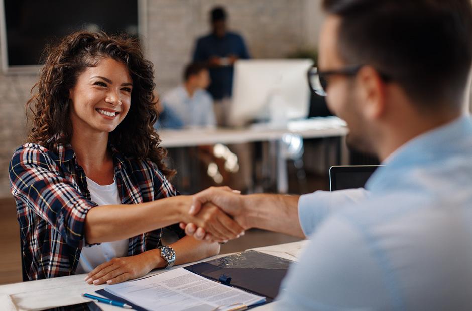 An image of a Young woman signing contracts and handshake with a manager