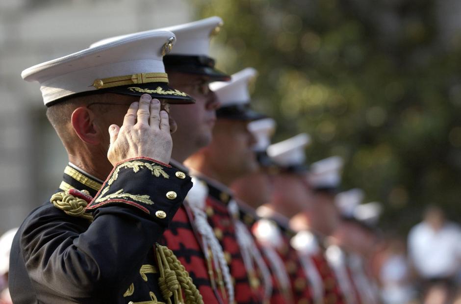 A group of Marines in uniform standing in line and saluting.
