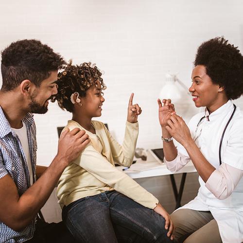 Smiling deaf girl learning sign language at doctor's office