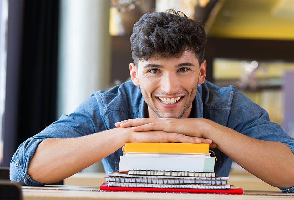 Young man leans on stack of books