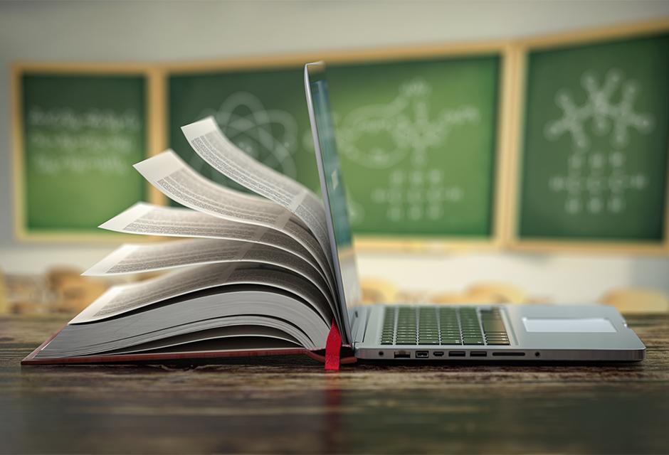 E-learning online education or internet encyclopedia concept. Open laptop and book compilation in a classroom. 