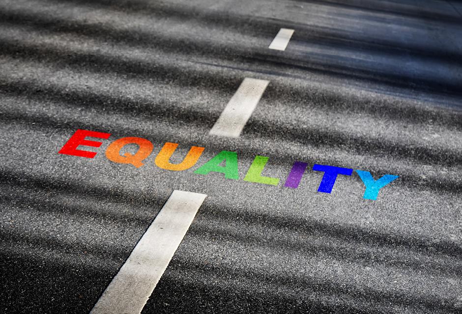Equality word with white dividing lines on black asphalt road surface with sunlight 