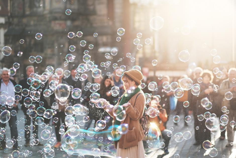 A woman standing in a crowd surrounded by bubbles.