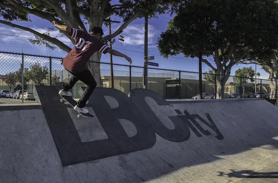 A skateboarder in a skate park with the words LB City on a ramp.