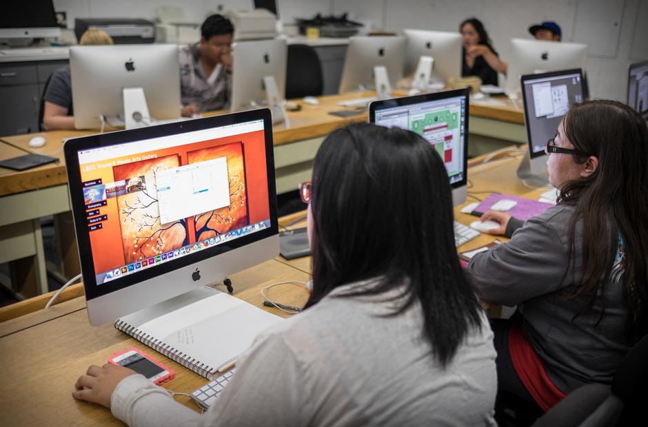 A group of students working on graphic design projects in a computer lab.