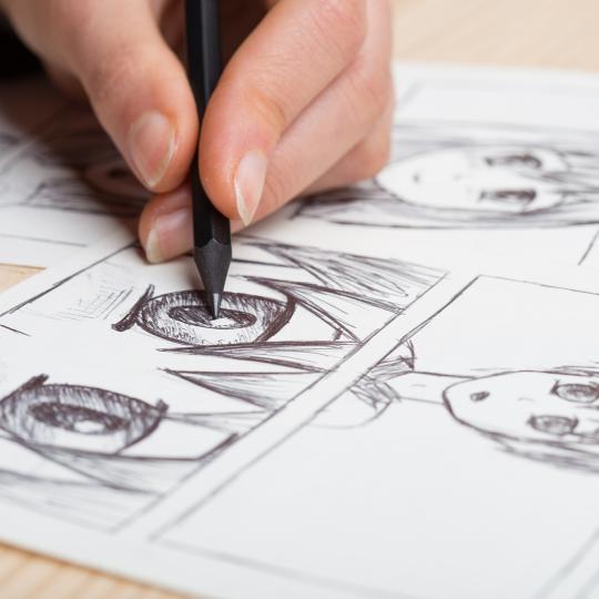 Artist drawing an anime comic book in a studio.